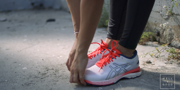 hands grabbing front of asics shoes while stretching