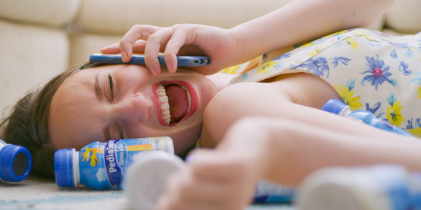 actor rachel ravel in character laughing on the phone surrounded discarded bottles